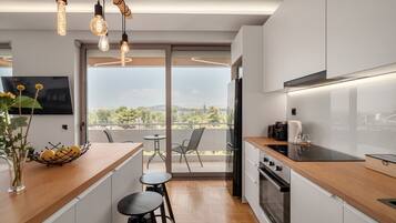 A modern kitchen with a wooden countertop, a built-in oven, and a large window overlooking a balcony.