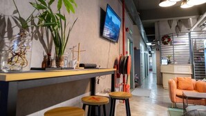 Een modern interieur met een bar, zitplaatsen en een televisiescherm.