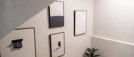 Una pared con cuatro obras de arte enmarcadas, una planta en maceta y un letrero con la palabra 'HOTEL' a la derecha.