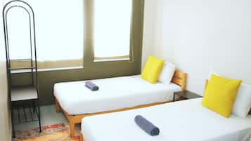 Una habitación con dos camas individuales, un escritorio y una silla.