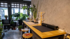 Een bar met krukken, een toonbank en verschillende planten.