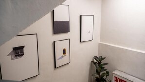 Een hotelgangen met kunstwerken in lijsten aan de muren, een potplant en een bord met de naam van het hotel.