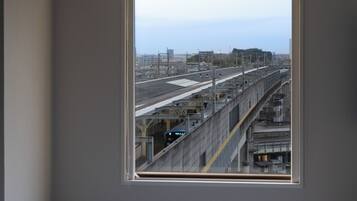Vista desde una ventana de un andén de estación de tren, con vías y un tren.