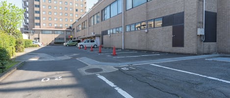 A parking lot with marked lanes and traffic cones, adjacent to a building with large windows and a brick facade.