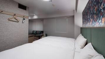 Habitación de hotel con una cama grande, un escritorio, una silla y un armario.