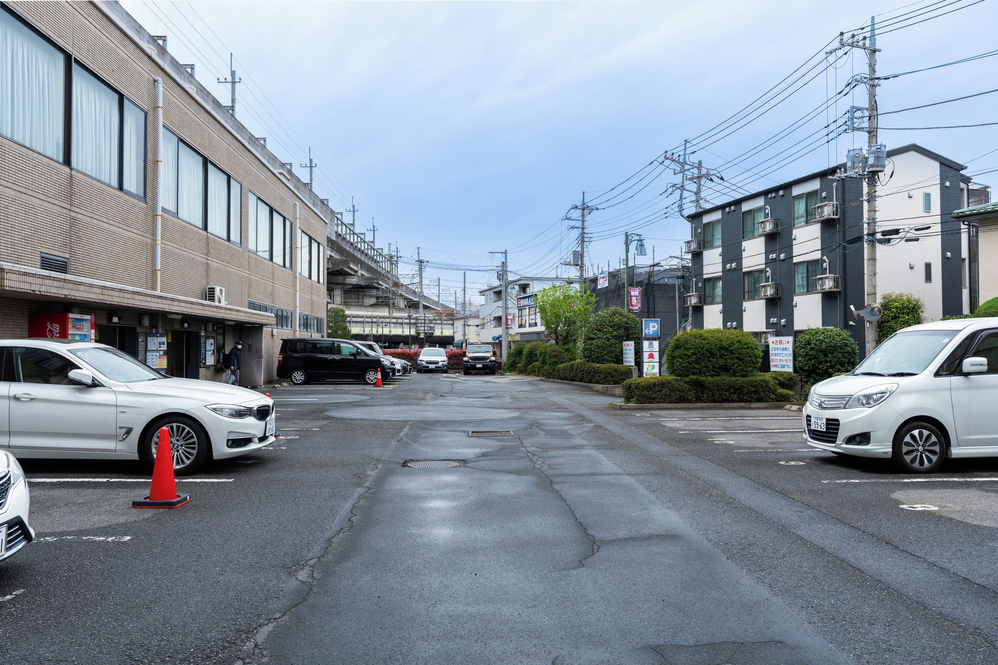 Una calle con coches aparcados, edificios y postes de electricidad.