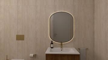 Un baño con un lavabo rectangular, un espejo con marco iluminado, un perchero para toallas y un dispensador de papel higiénico.