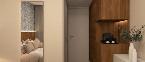 A hotel room with a bed, bedside table, and a wall-mounted shelf with a coffee machine and cups.