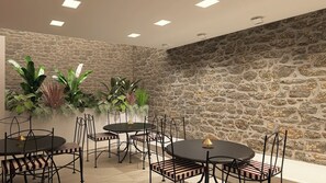 Una sala conferenze con parete in pietra, diversi tavoli con sedie e piante in vaso.