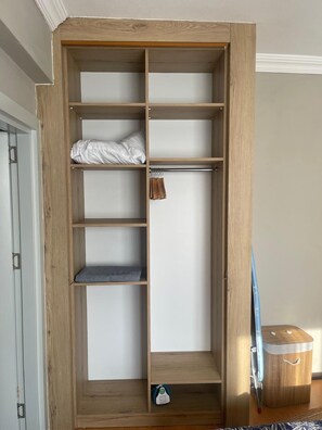 Ein Holfschrank mit mehreren Einlegeböden und Kleiderstange, eine kleine Ablagebox und eine blaue Tasche.