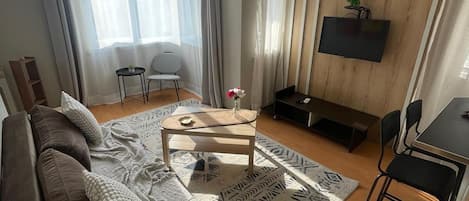 Un salon moderne avec un canapé, une table basse et un téléviseur.
