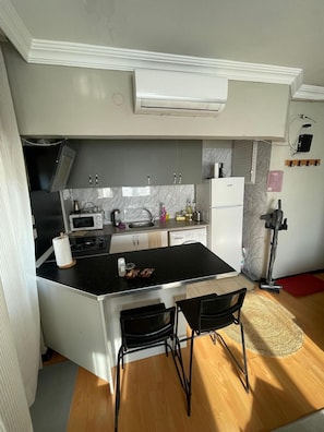 A compact kitchen with a central island, a microwave, a sink, and a refrigerator. - Cozy 1-bedroom flat in near Old Town with AC and balcony (Antalya)