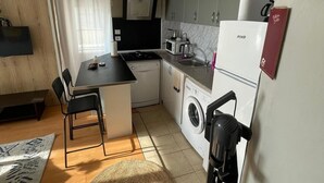A compact kitchen with a dining area, a washing machine, and a microwave. - Cozy 1-bedroom flat in near Old Town with AC and balcony (Antalya)