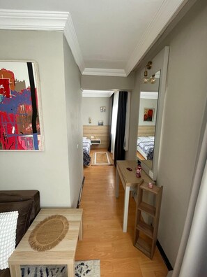 A narrow hallway leading to a bedroom with a bed, a bedside table, and a mirror. - Cozy 1-bedroom flat in near Old Town with AC and balcony (Antalya)