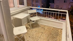 A balcony with a white metal railing, a small table, and two chairs. - Cozy 1-bedroom flat in near Old Town with AC and balcony (Antalya)