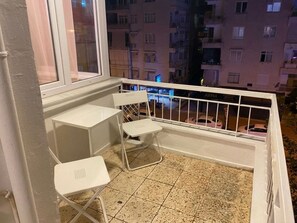 Ein Balkon mit weißem Metallgeländer, einem kleinen Tisch und zwei Stühlen.