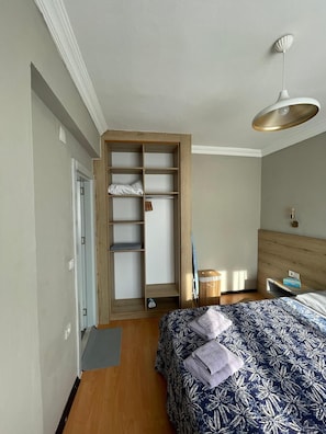 A bedroom with a bed, a wooden wardrobe, a bedside table, and a hanging light fixture. - Cozy 1-bedroom flat in near Old Town with AC and balcony (Antalya)