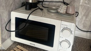 A compact microwave oven with a digital display and control panel, placed on a granite countertop. - Cozy 1-bedroom flat in near Old Town with AC and balcony (Antalya)
