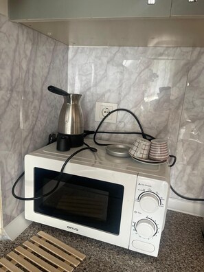 Eine kompakte Mikrowelle mit digitalem Display und Bedienfeld, auf einer Arbeitsplatte aus Granit platziert.