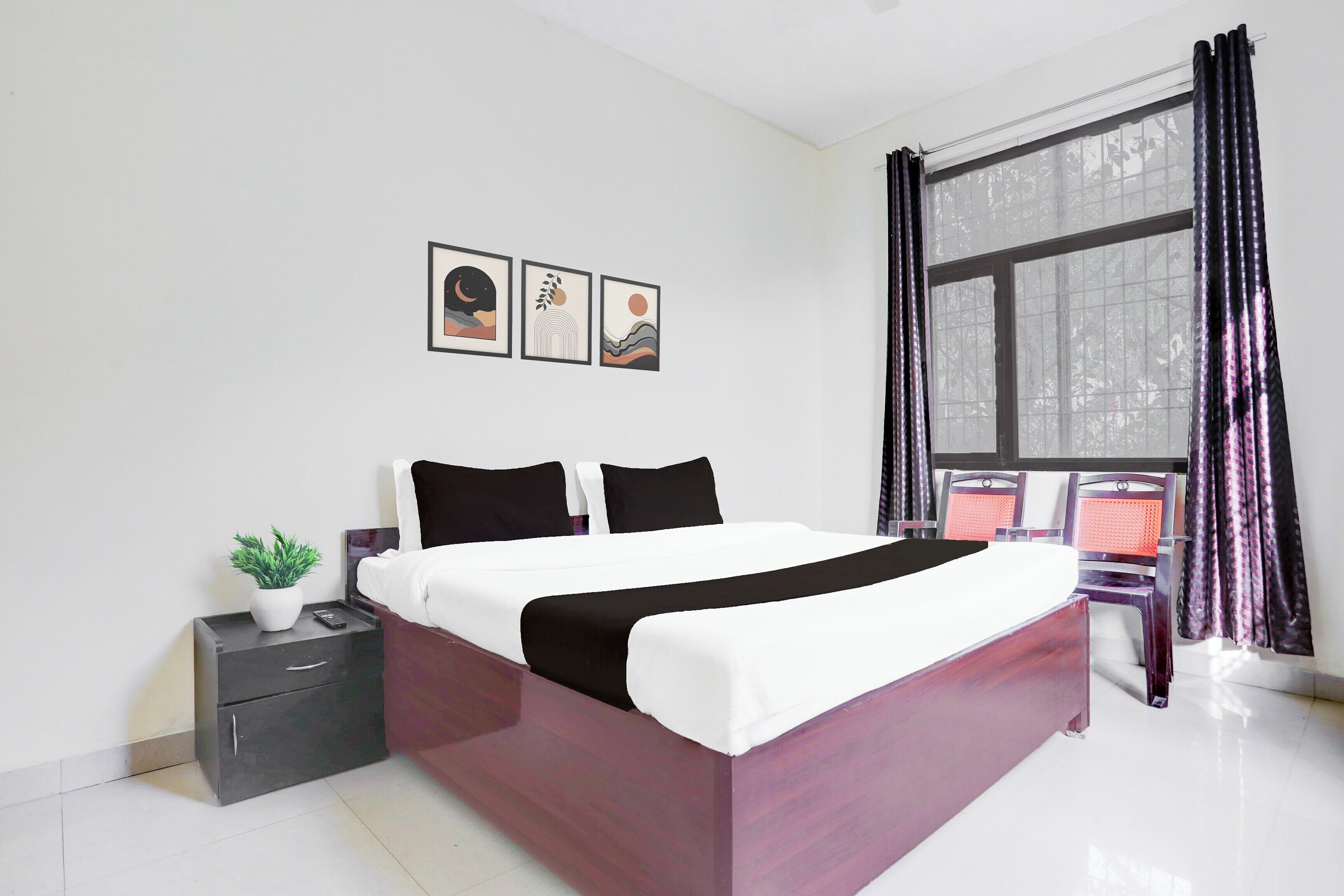 A modern bedroom with a bed, a nightstand, a potted plant, and a window with curtains.
