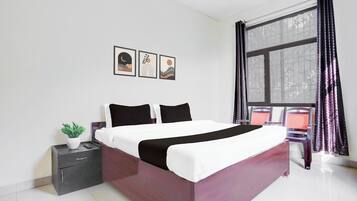 A modern bedroom with a bed, a nightstand, a potted plant, and a window with curtains.