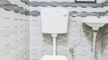 A bathroom with a white toilet, a sink, and a marble-patterned wall.