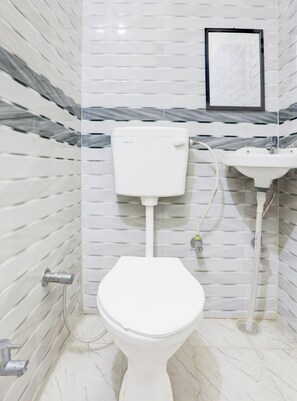 A bathroom with a white toilet, a sink, and a marble-patterned wall.