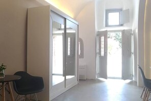A room with a sliding door, a small table with a chair, and a window with a view of greenery outside. - Villa LuxL Winery Villa (Mesaria)