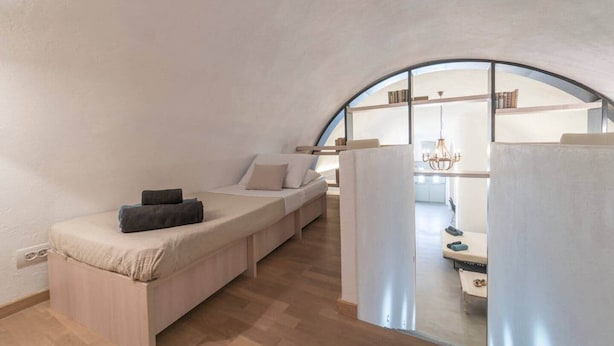 Habitación acogedora de techos curvos, con cama empotrada y vista a una cocina a través de un mamparo de vidrio.