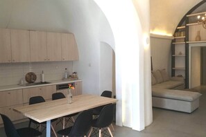 A modern kitchen with a dining area, featuring a wooden table and chairs, and a built-in seating area with a sofa. - Villa LuxL Winery Villa (Mesaria)