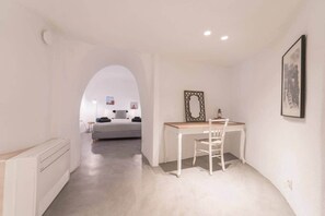Ein Schlafzimmer mit Bett, Schreibtisch und Stuhl. An der Wand ist eine Heizung und ein Bilderrahmen angebracht.