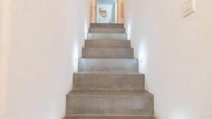 Una escalera con barandilla que lleva a un rellano con una puerta y un ventanal circular.