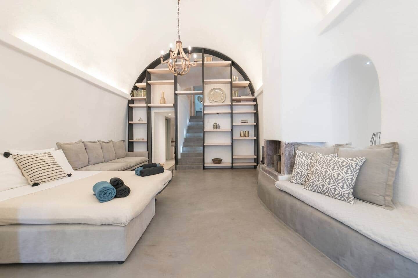 A modern interior with a sofa set, a chandelier, and a staircase leading to a loft area.