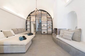 Un intérieur moderne avec un ensemble de canapés, un lustre et un escalier menant à une mezzanine.