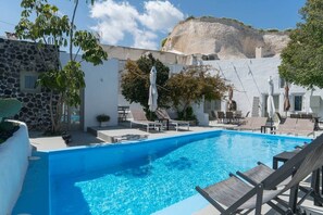 A swimming pool with lounge chairs and umbrellas, surrounded by a stone wall and vegetation. - Villa LuxL Winery Villa (Mesaria)