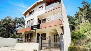A multi-story building with a balcony, a sign indicating it is a company-serviced collection, and a gated entrance.