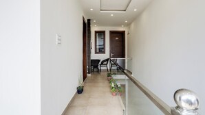 A corridor with a glass railing, potted plants, and a door marked with the number 201.