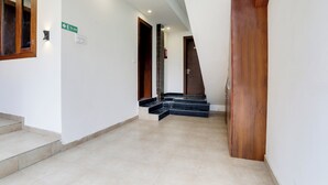 A corridor with a wooden door, a staircase, and a green exit sign.