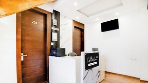 A reception area with a reception desk, a wooden door labeled '204', and a wall-mounted television.