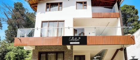 A two-story building with a balcony, a sign indicating 'Collection Company-Serviced', and a gated entrance.