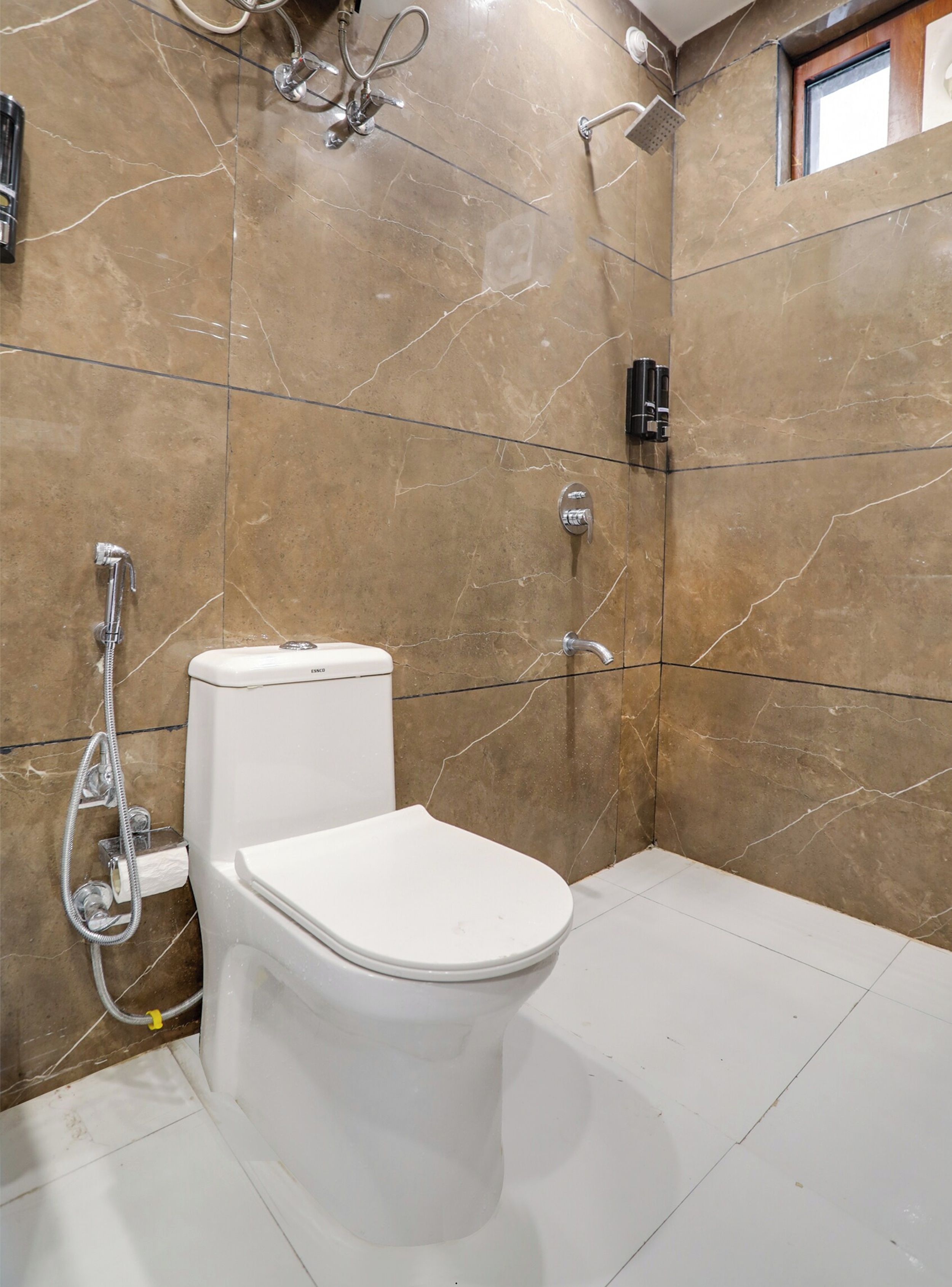 A bathroom with a toilet, shower, and a marble wall.