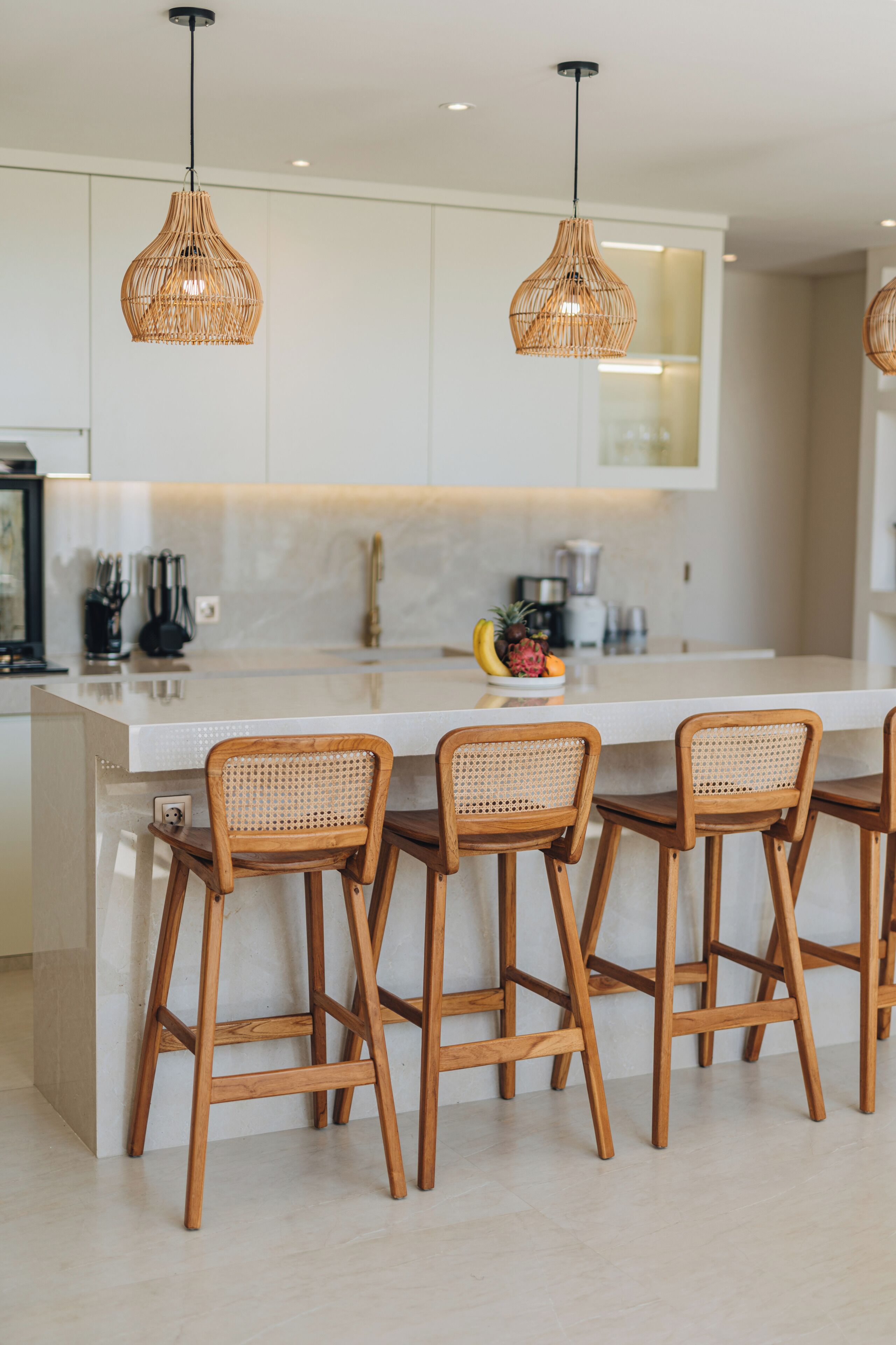 A modern kitchen with a central island, bar stools, and pendant lighting.