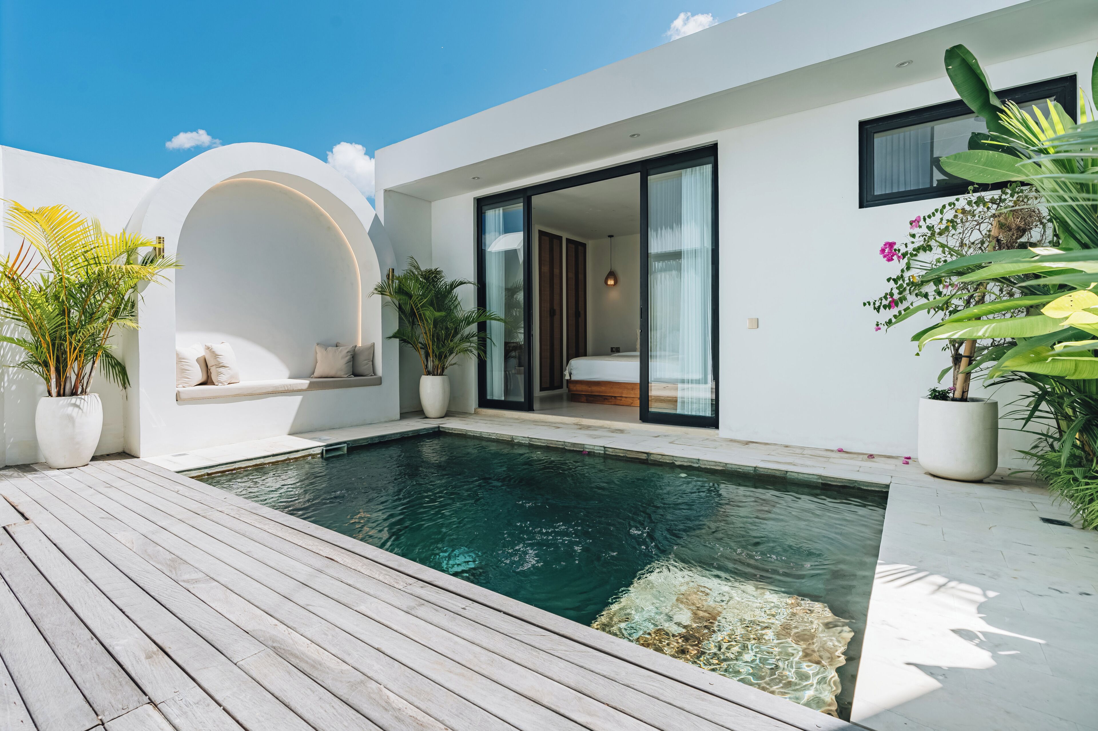 A modern house with a swimming pool, a built-in bench, and potted plants.