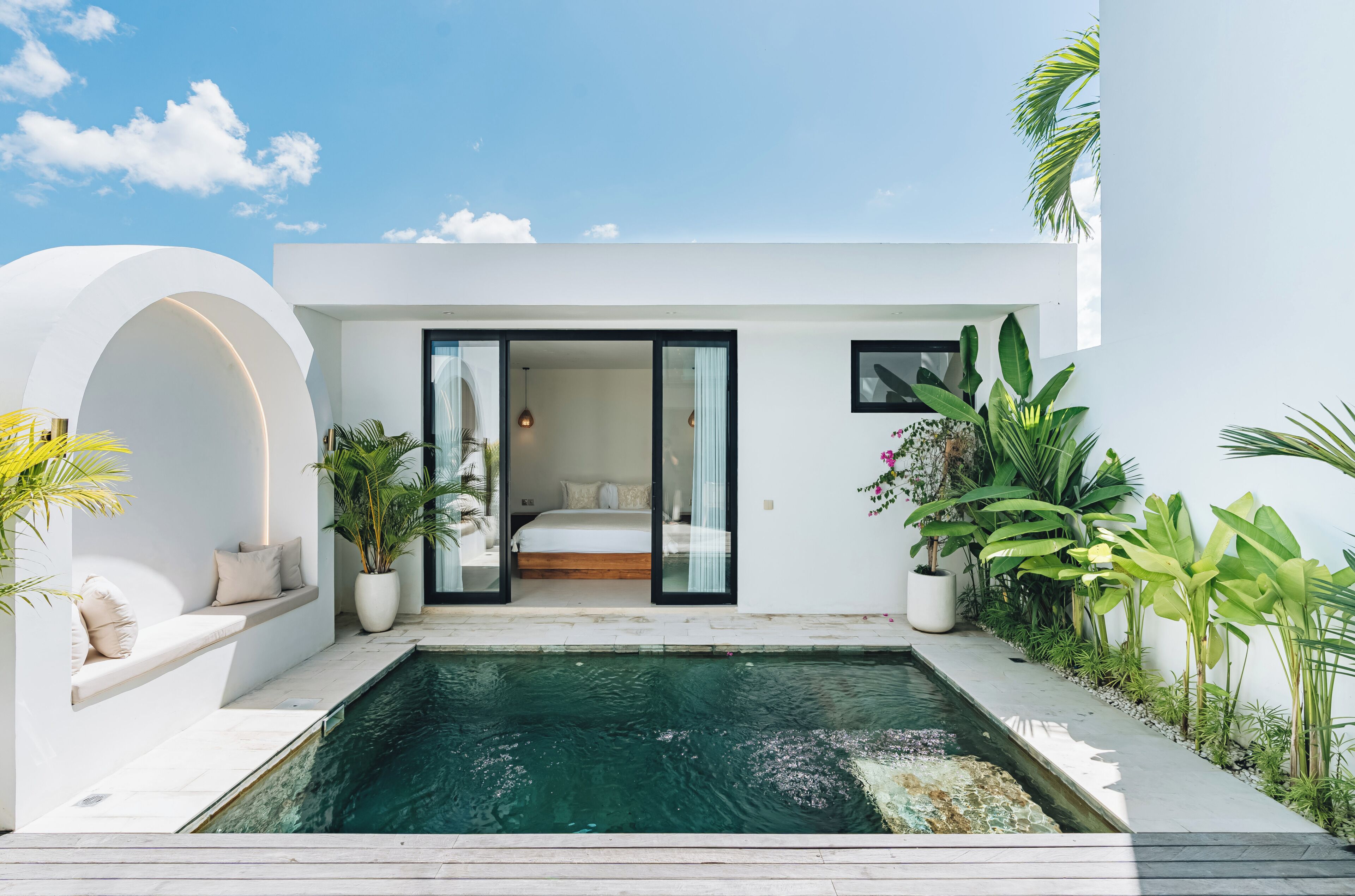 Una casa moderna amb una piscina, un dormitori amb llit i plantes en testos.