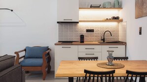Moderni keittiö, jossa on valkoiset kaapit, puinen ruokapöytä ja sininen tuoli.