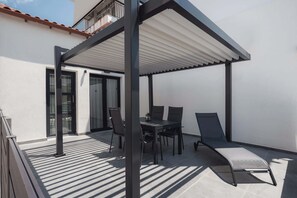 A covered patio with a table and chairs, a glass door, and a white wall. - Ag. Ma Maria Suite - Chalkidiki w/ Priv Parking (Nikiti)
