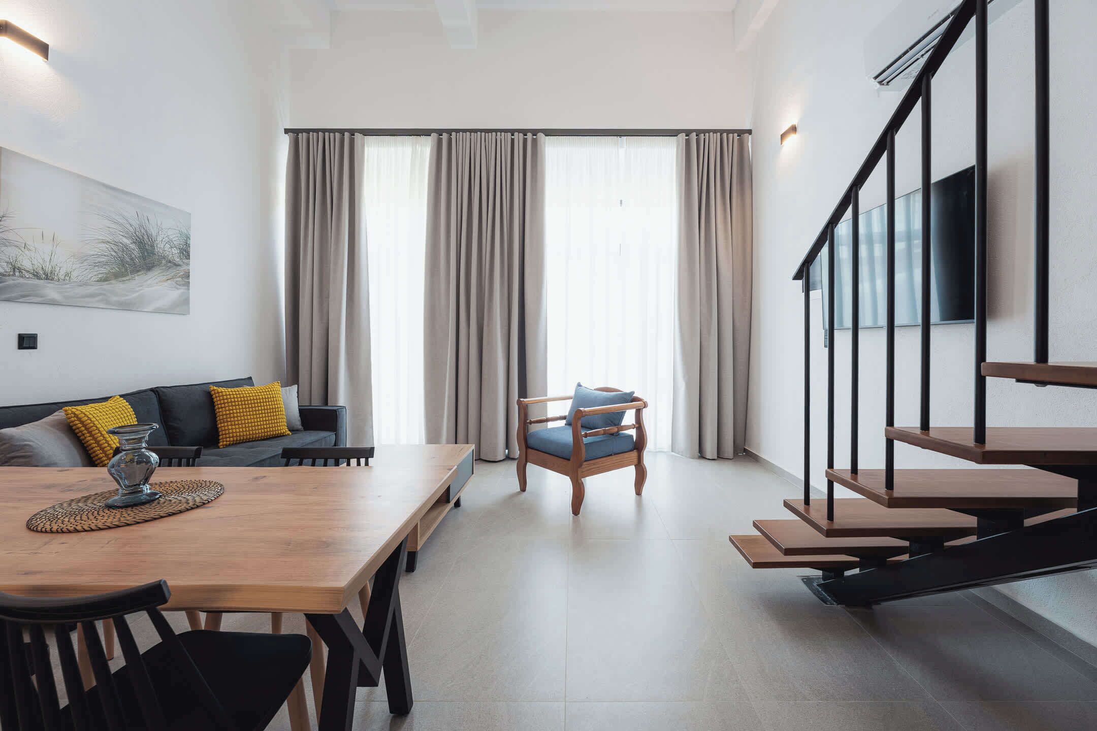 Un espace de vie moderne comprenant un coin repas, un canapé, un fauteuil et un escalier.