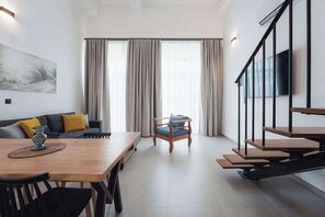 Um espaço de estar moderno com área de jantar, um sofá, uma poltrona e uma escada.