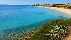 A coastal landscape with clear blue waters, sandy beach, and sparse vegetation. - Ag. Ma Aggelos Suite - Chalkidiki w/ Priv Parking (Nikiti)