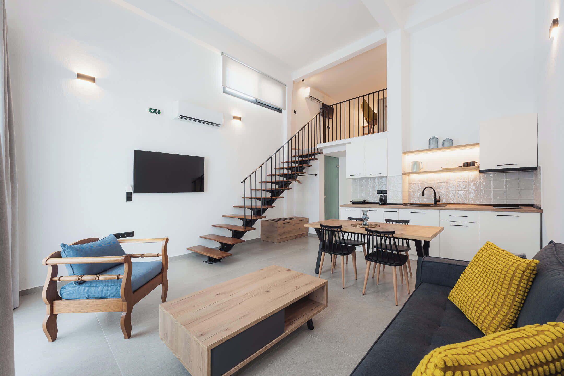 A modern living space with a staircase, a dining area, and a kitchen.